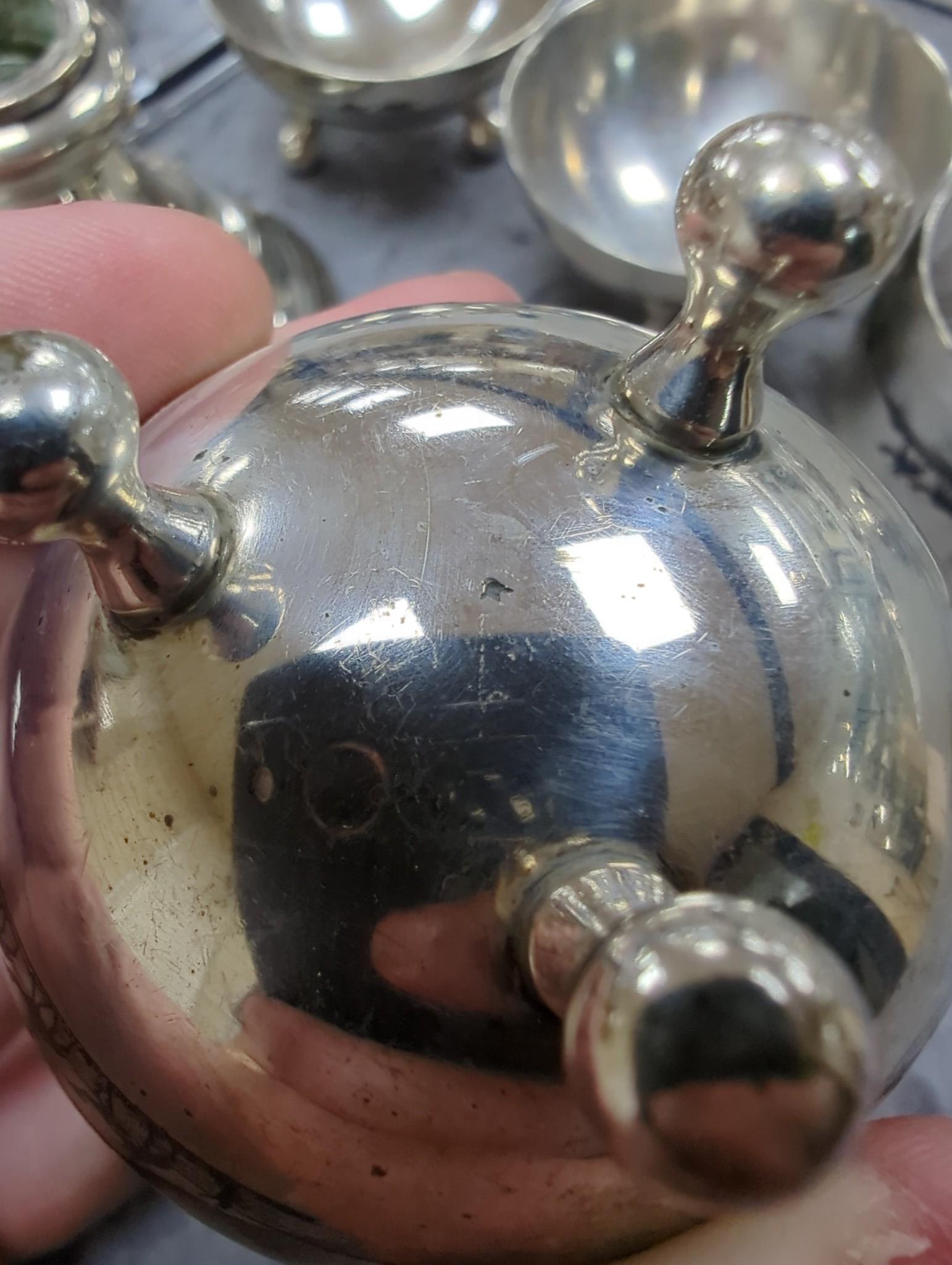 Thirteen assorted Iraq white metal and niello condiments, circular box, five similar napkin rings, a brooch and a pair of similar (damaged) candlesticks.